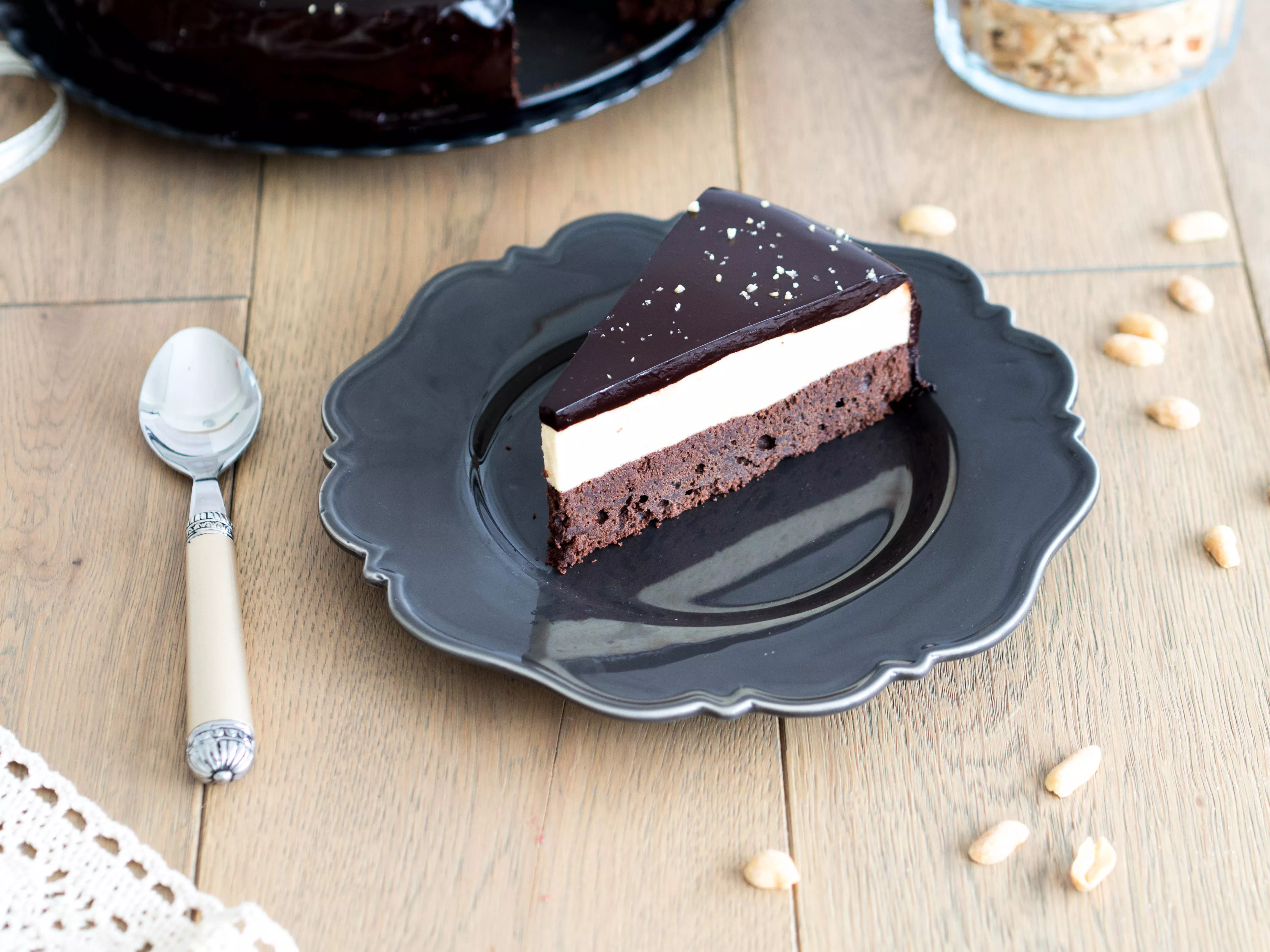 kawałek tortu czekoladowego na czekoladowym spodzie, z musem z masła orzechowego i czekoladową polewą lustrzaną, posypanego posiekanymi orzeszkami ziemnymi - Wszystkiego Słodkiego