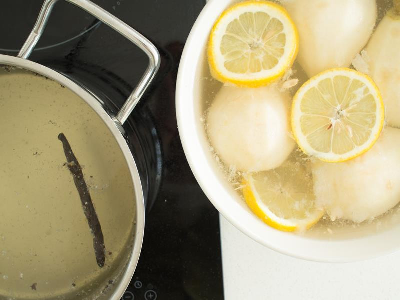gotujący się syrop, miska z gruszkami w wodzie z cytryną