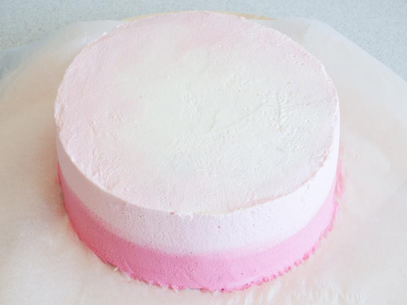 jasnoróżowy i ciemnoróżowy krem śmietankowy rozprowadzone na bokach i wierzchu tortu tworzące wzór obmre
