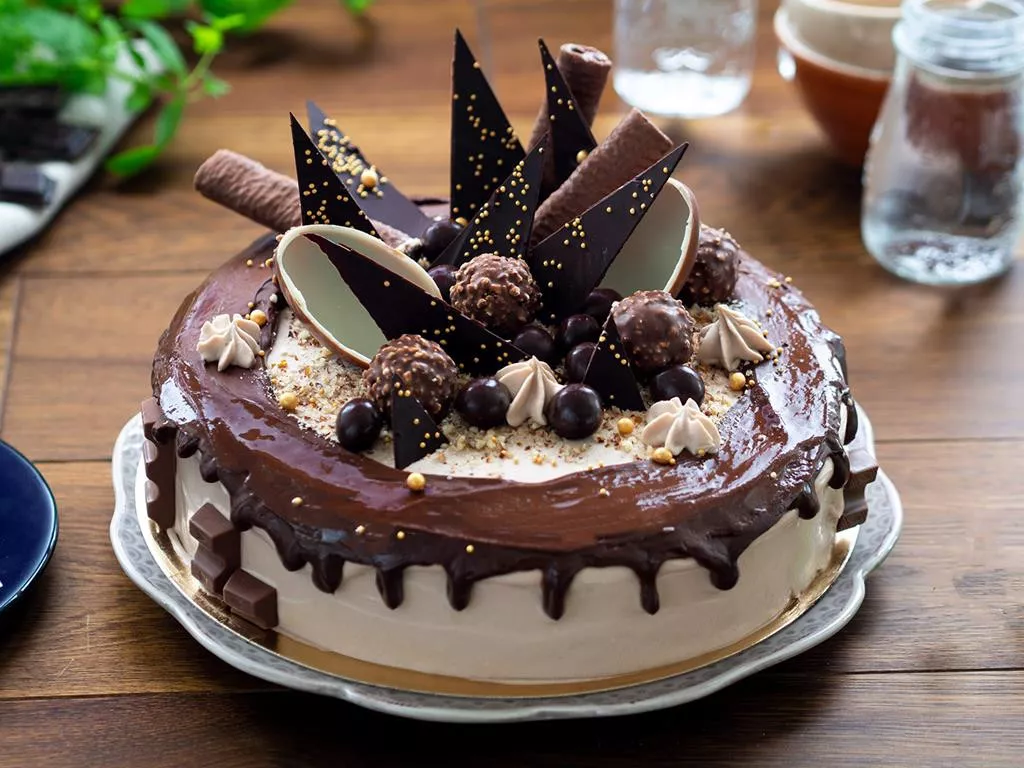 Czekoladowo-orzechowy tort Drip Cake na bazie biszkoptu kakaowego, przełożonego kremem czekoladowo-orzechowym ze zmielonymi orzechami laskowymi i polanego polewą czekoladową, tort ozdobiony jajkami czekoladowymi, posypką blask pereł dr. oetkera
