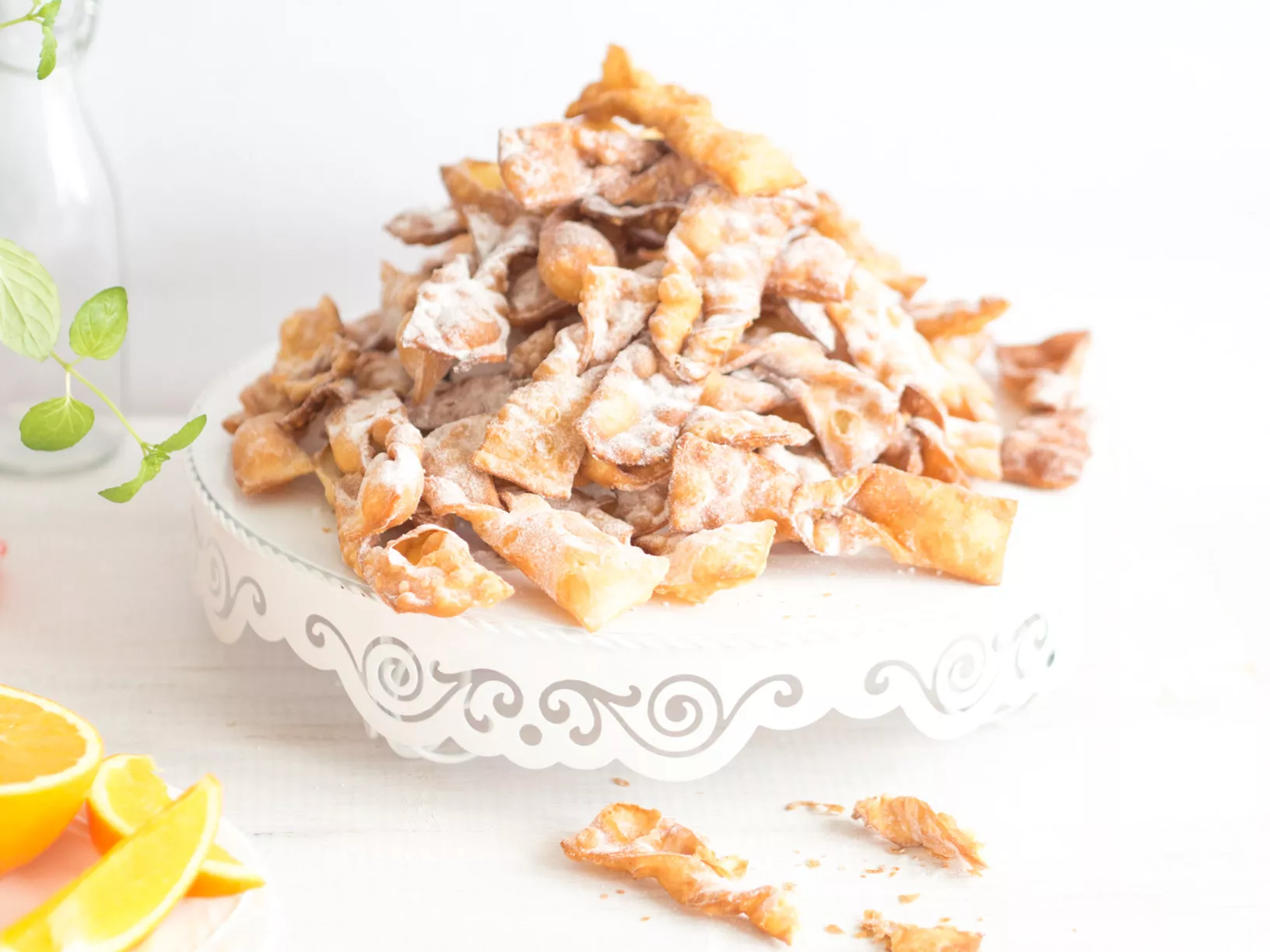 Faworki pomarańczowe z cukrem pudrem na paterze - Wszystkiego Słodkiego