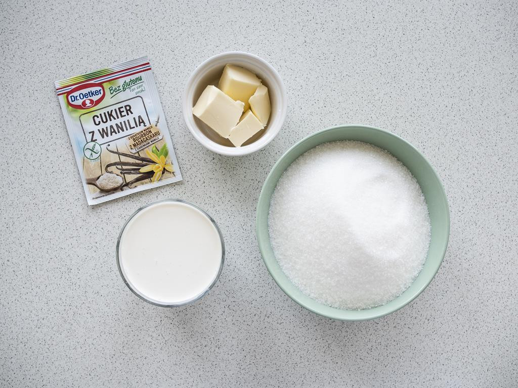 cukier, śmietanka i masło w osobnych miseczkach oraz opakowanie cukru z wanilią bez glutenu od dr. oetkera