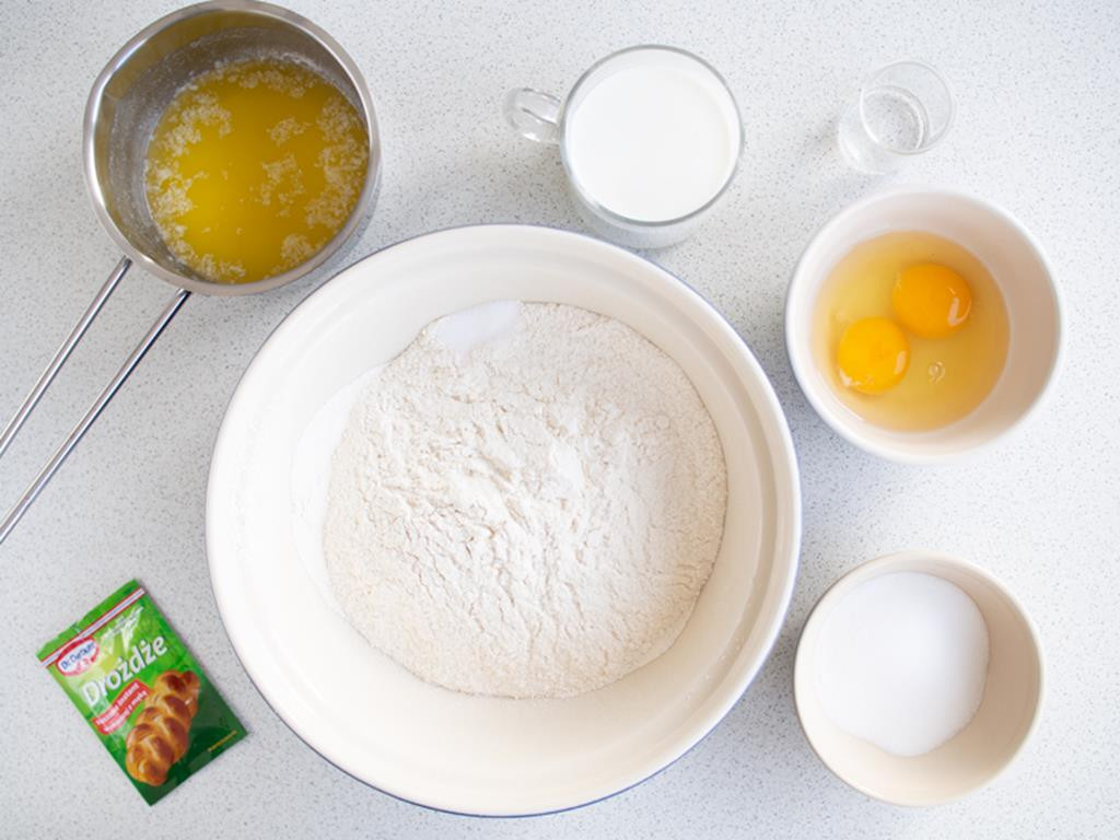 mąka i sól w dużej misce, obok opakowanie drożdży suszonych instant dr. oetkera, jajka i cukier w osobnych miseczkach, mleko w szklance, rozpuszczone masło w rondelku i spirytus w kieliszku