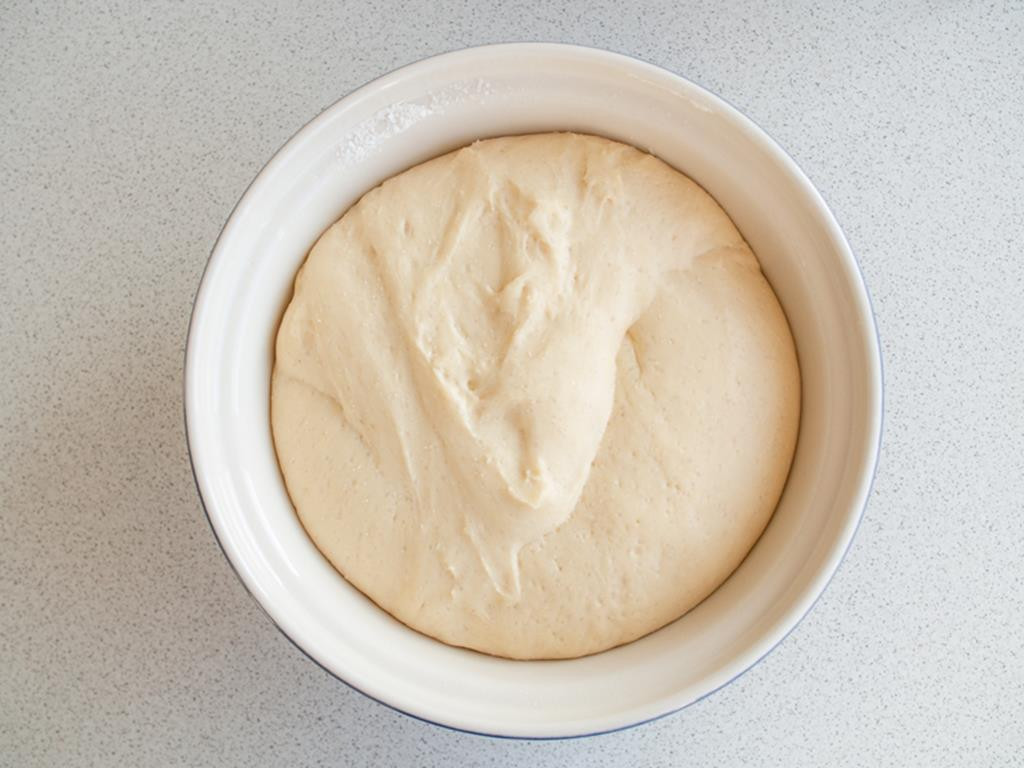 wyrośnięte ciasto drożdżowe na pączki z budyniem i owocowym lukrem w misce