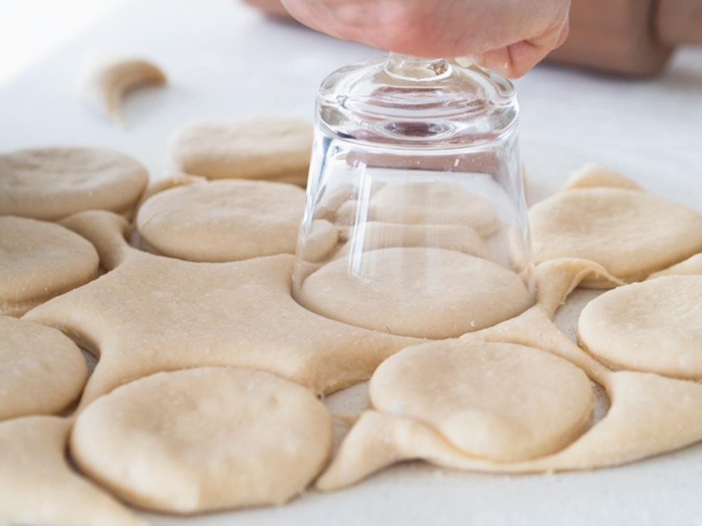 wycinanie krążków z ciasta drożdżowego na pączki za pomocą szklanki
