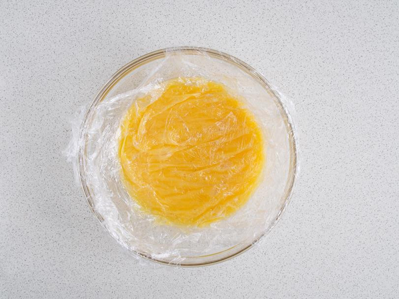 gotowy krem lemon curd w szklanej misce przykryty folią spożywczą w kontakcie