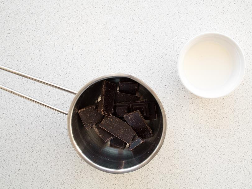połamana czekolada w rondelku i śmietanka w miseczce
