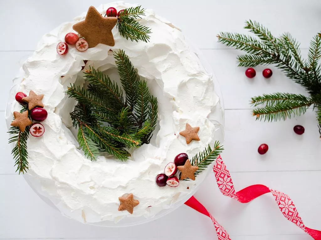 świąteczna beza z żurawiną na boże narodzenie nadziewana kremem z mascarpone z dodatkiem wanilii oraz konfiturą żurawinową, udekorowana pierniczkami, świeżą żurawiną oraz gałązkami świerku - wszystkiego słodkiego