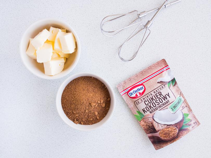 cukier kokosowy i masło pokrojone w kostkę w osobnych miseczkach, obok opakowanie cukru kokosowego nierafinowanego dr. oetkera oraz mieszadła miksera