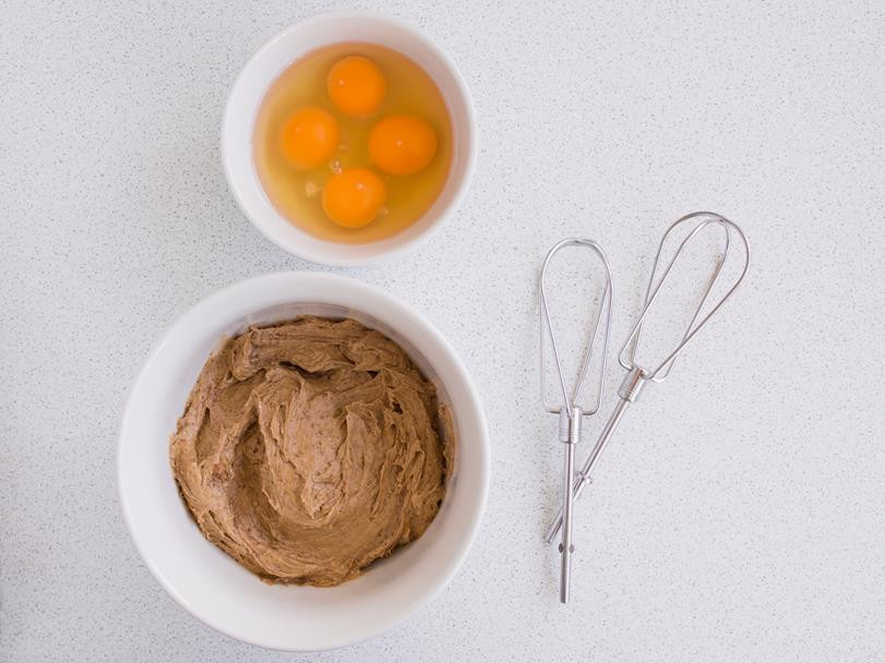 masło utarte z cukrem kokosowym w misce, obok jajka w drugiej misce oraz mieszadła miksera
