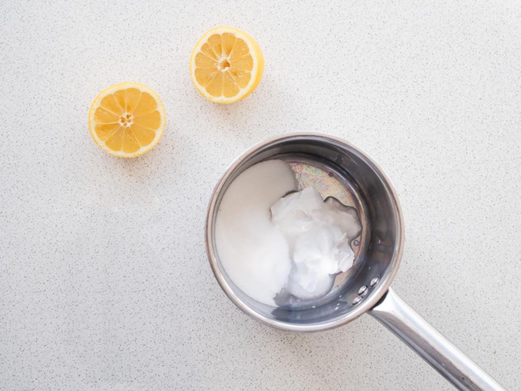 mleko kokosowe i cukier w rondelku, obok cytryna przekrojona na pół