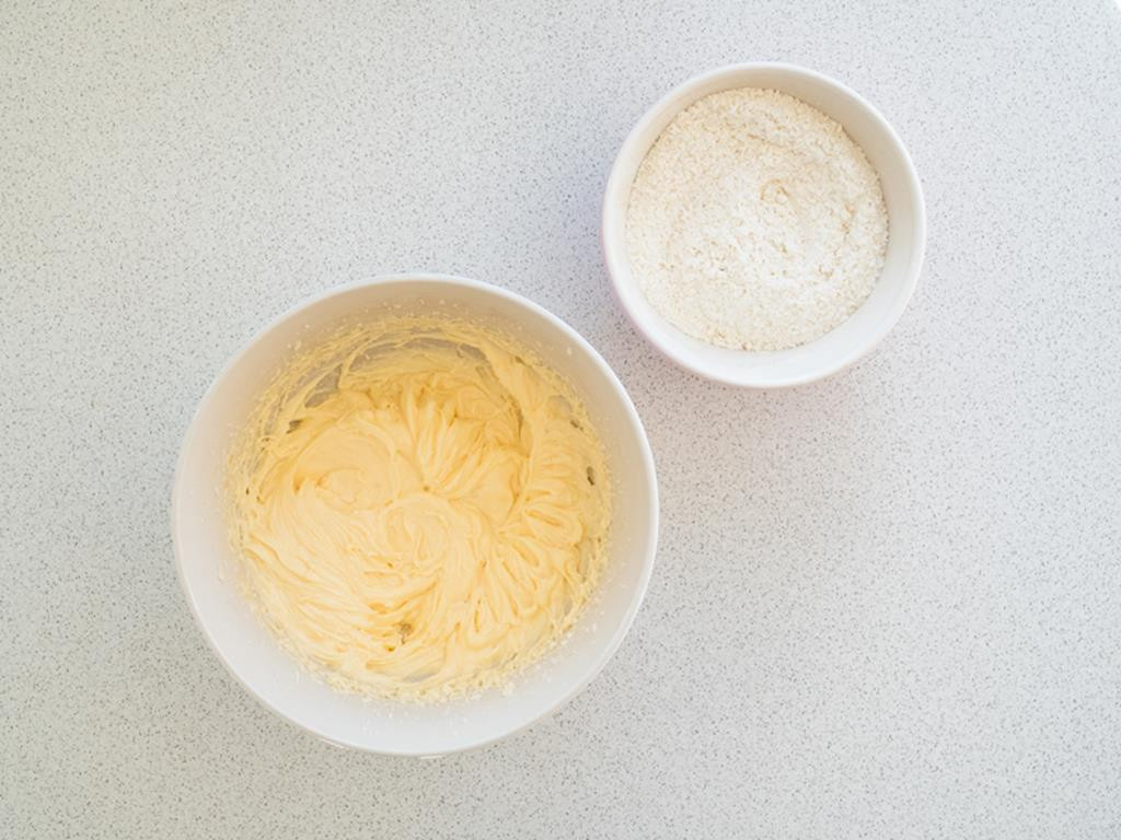 masło utarte z cukrem i jajkami w miseczce, obok mąka pszenna w drugiej miseczce