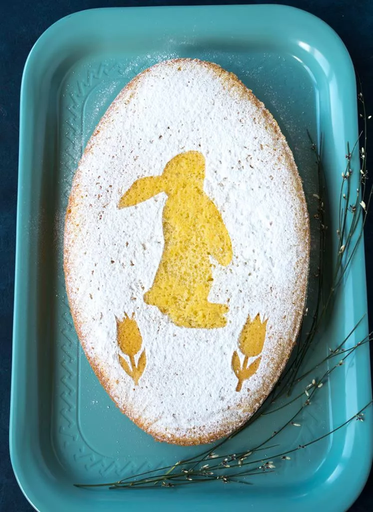 wielkanocna babka cytrynowa z dodatkiem skórki z cytryny, upieczona w formie w kształcie jaja, ozdobiona cukrem pudrem i motywem zajączka i kwiatów - Wszystkiego Słodkiego