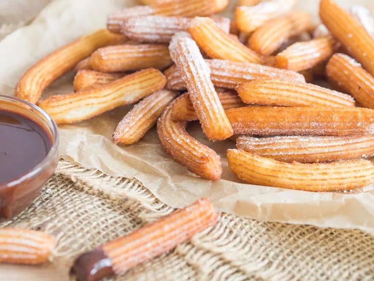 churros z sosem czekoladowo-pomarańczowym posypane cukrem pudrem - wszystkiego słodkiego