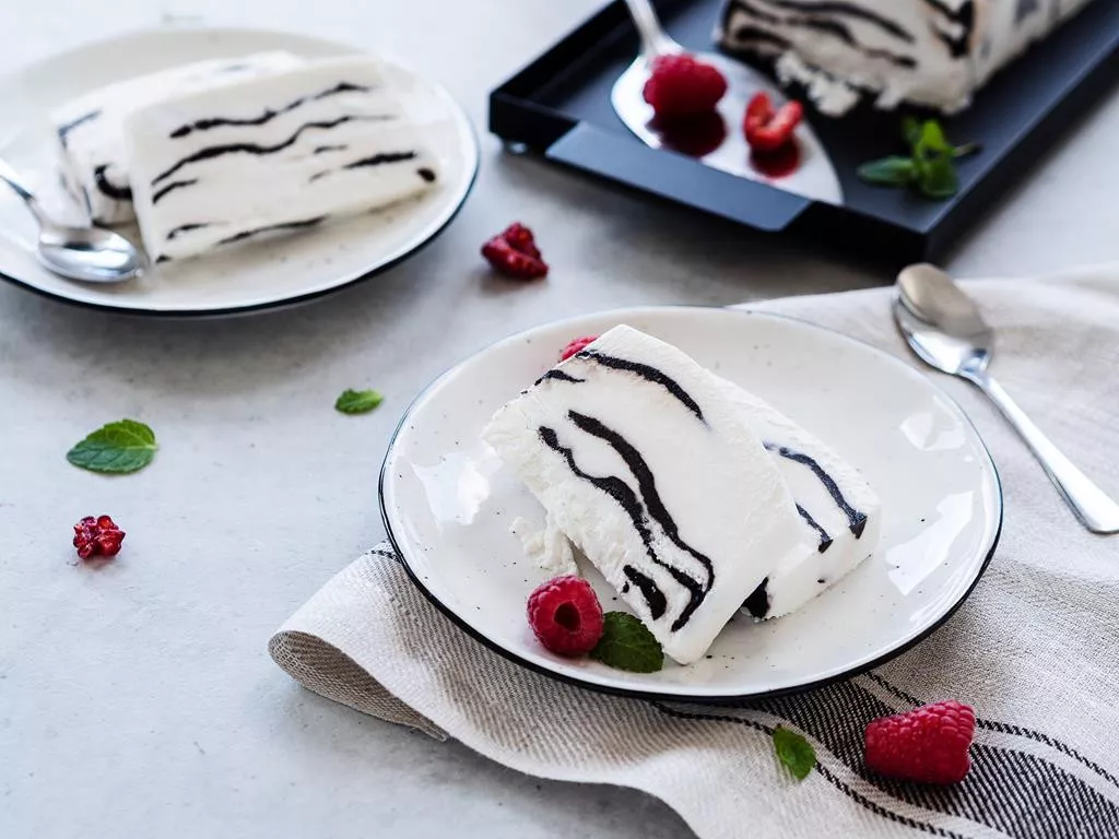 Lody kokosowa zebra podane na talerzyku z malinami