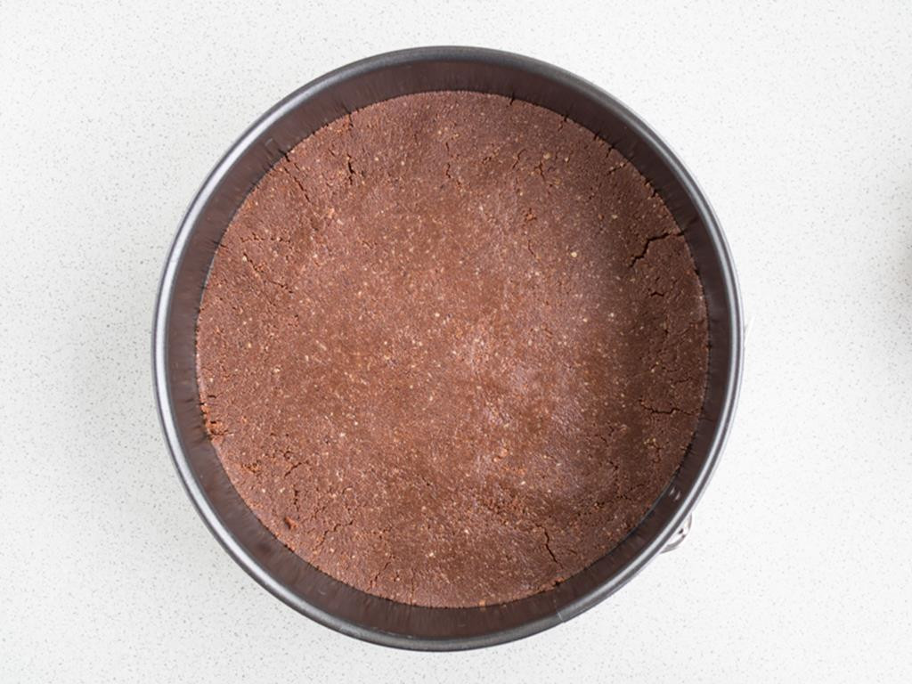 Zbożowe, kakaowe ciasteczka wymieszane z masłem wyłożone na spód tortownicy