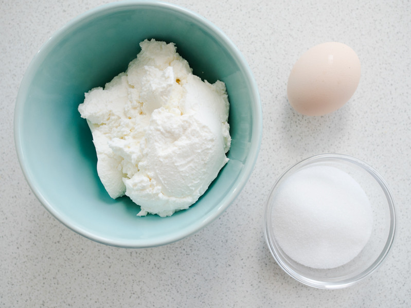 twaróg sernikowy w miseczce, cukier w drugiej miseczce, jajko