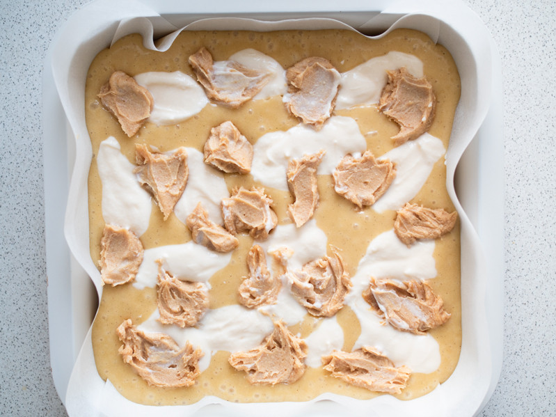 ciasto na blondies w formie do pieczenia z wyłożonymi kleksami z masy serowej i masła orzechowego