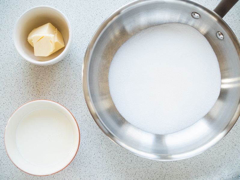 cukier na patelni, śmietanka w miseczce i masło w drugiej miseczce