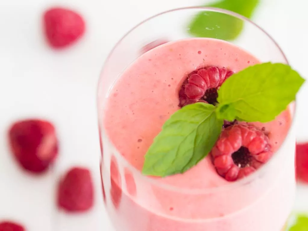 koktajl malinowo-truskawkowy na maślance ozdobiony świeżymi malinami i listkami mięty - wszystkiego słodkiego