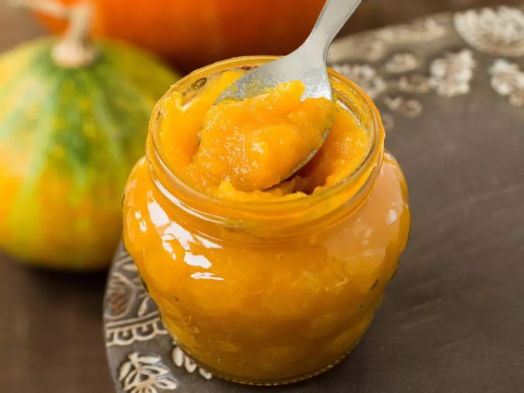 marmolada jabłkowo-dyniowa w słoiczku z łyżeczką, dynie w tle - wszystkiego słodkiego