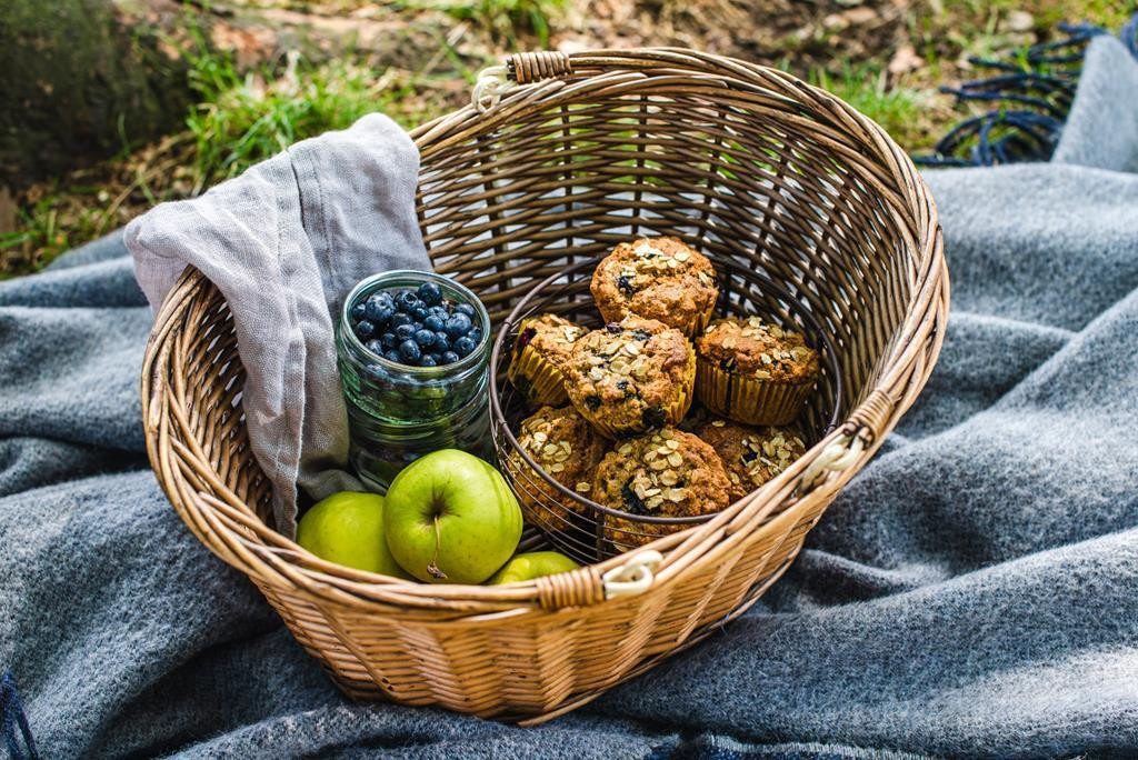 kosz piknikowy z muffinami, słoikiem jagód i jabłkami