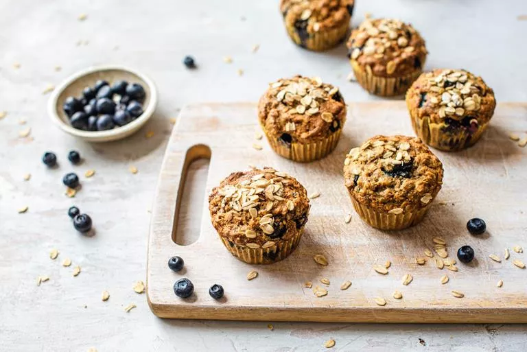 Wegańskie muffiny śniadaniowe z borówkami na drewnianej desce.