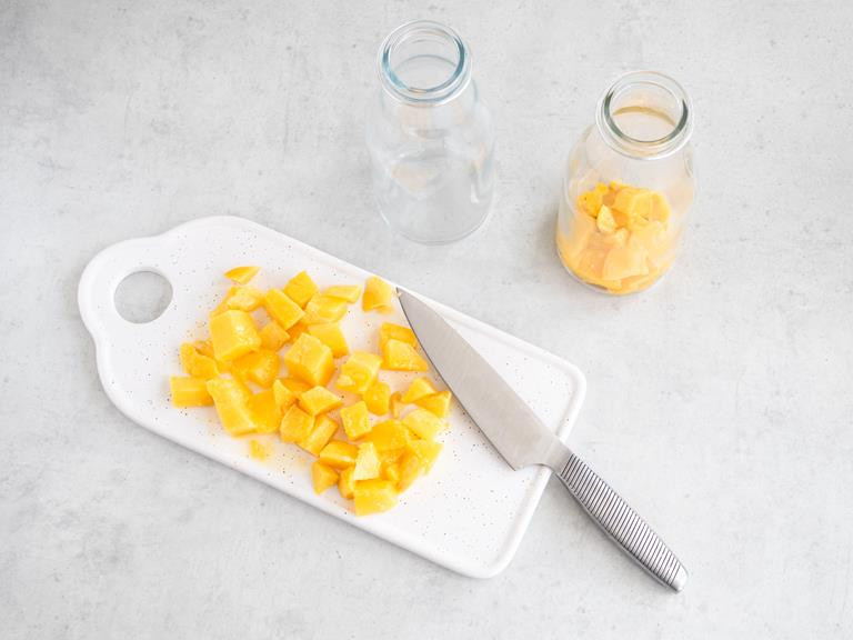 Pokrojone mango w kostkę na białej desce.