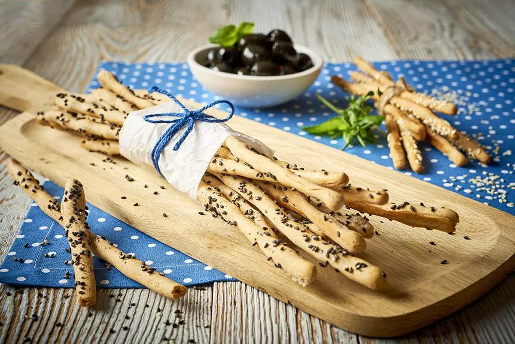 Paluszki z sezamem położone na drewnianej paterze