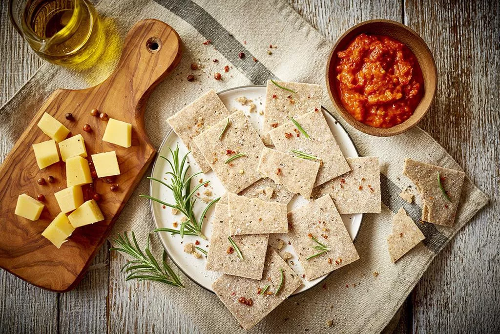 krakersy rozmarynowe bez glutenu pokrojone na kawałki, podane z serem