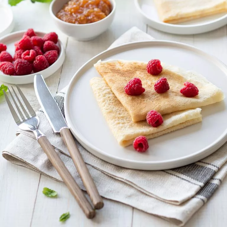 Naleśniki wegańskie na białym talerzu podane z malinami - Wszystkiego Słodkiego