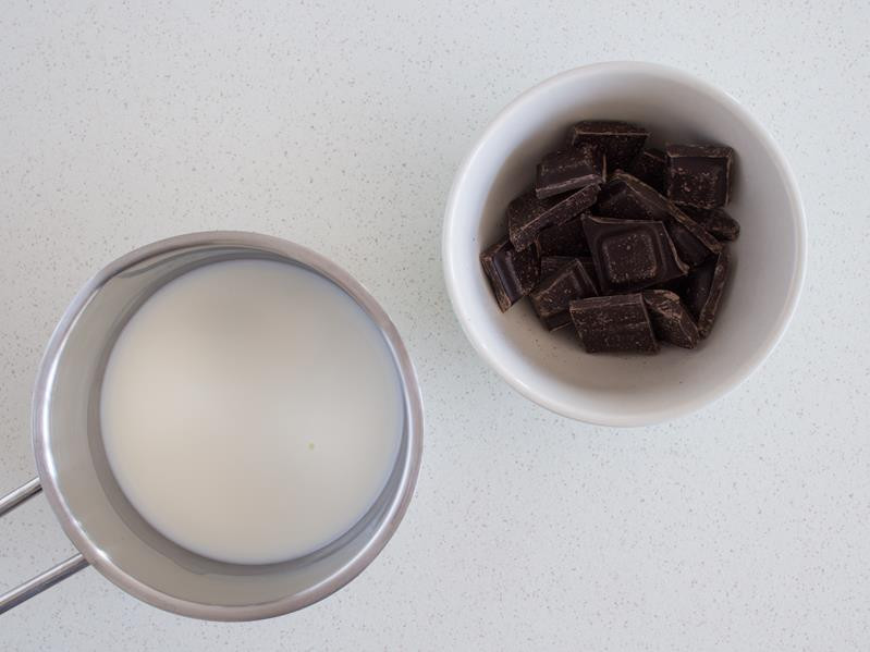 Mleko w garnku i pokruszona czekolada w miseczce.