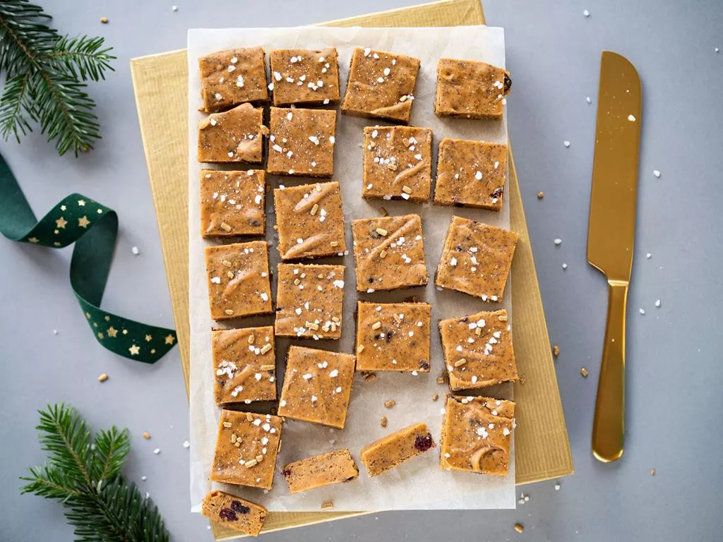 karmelowe kostki ułożone na papierze do pieczenia w bożonarodzeniowej scenerii - Wszystkiego Słodkiego