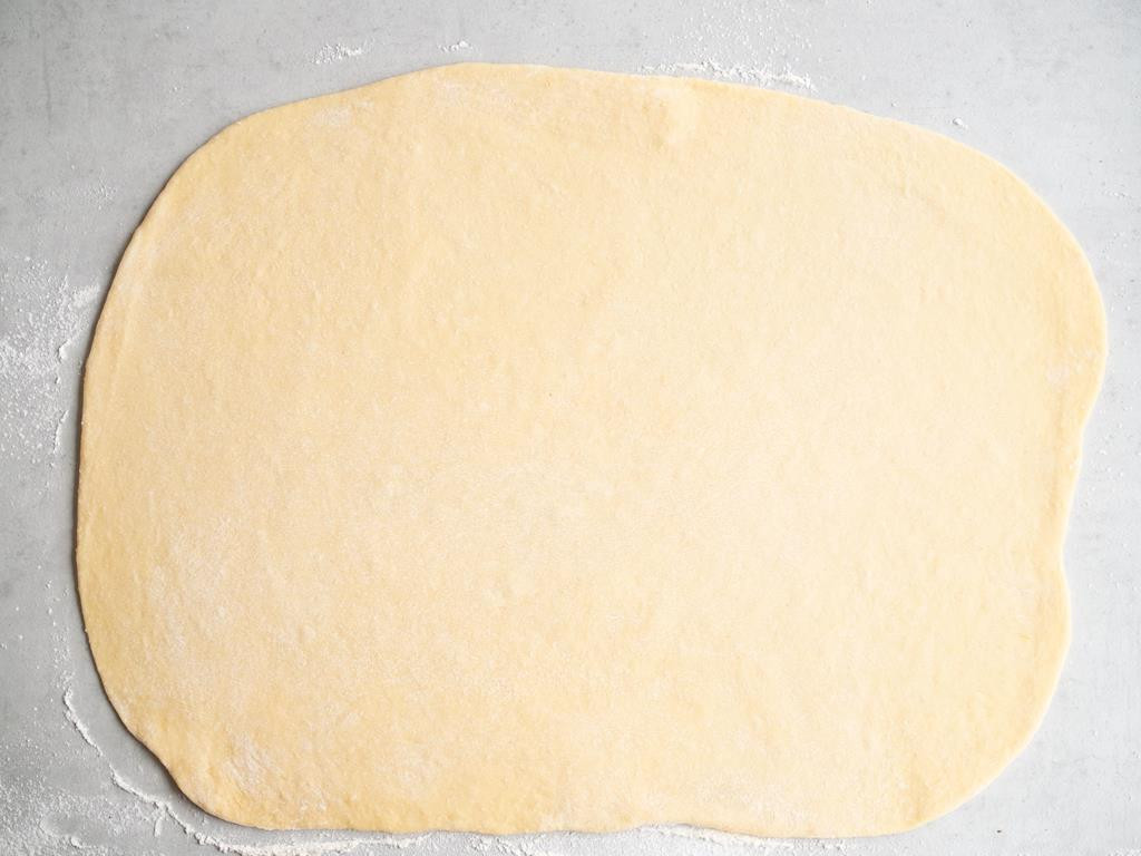 na stole rozwałkowane ciasto drożdżowe