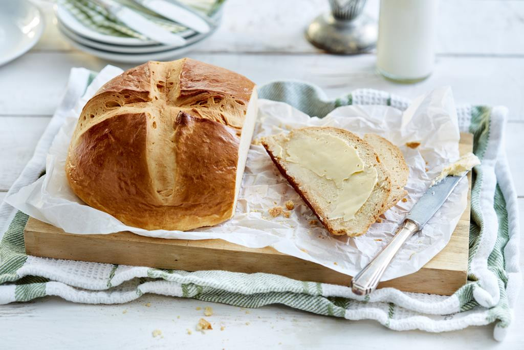 Chleb na drożdżach położony na desce do krojenia, posmarowany masłem