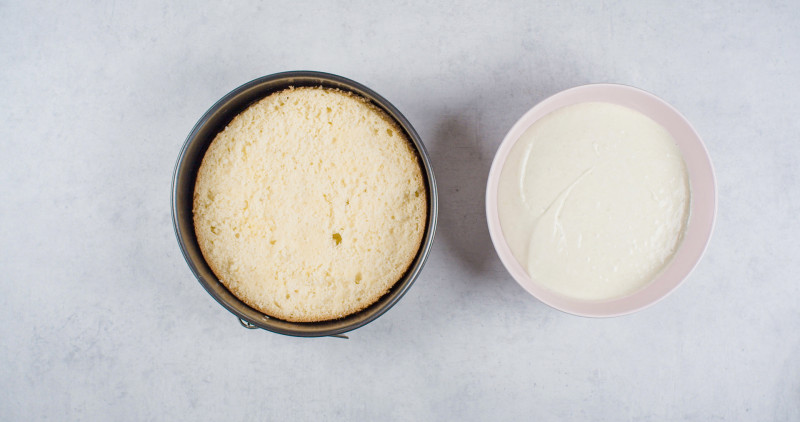 jeden z blatów biszkoptu ułożony z powrotem w czystej tortownicy i obok miska z kremem z serka mascarpone, galaretki agrestowej i musu gruszkowego