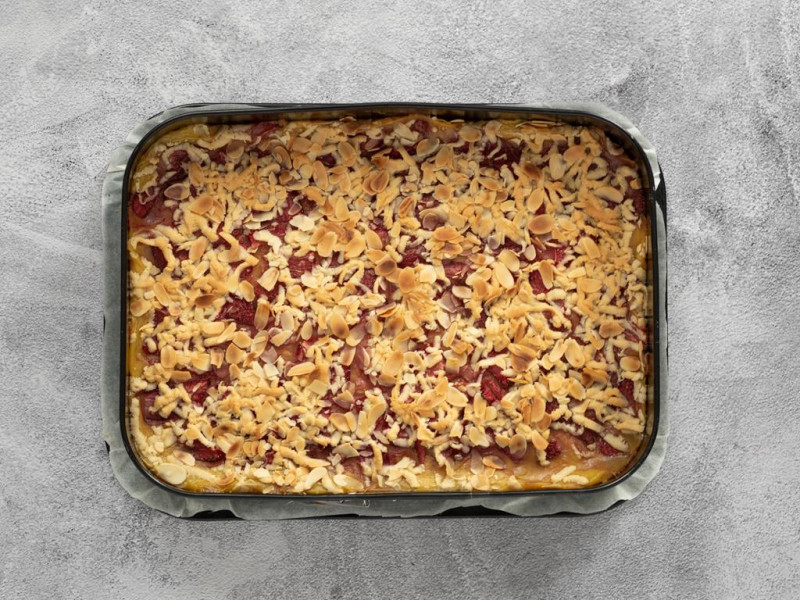 Upieczone ciasto kruche z budyniem, truskawkami i kruszonką.
