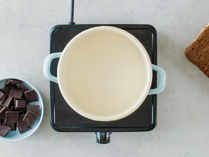 Śmietanka w garnuszku i pokrojona gorzka czekolada