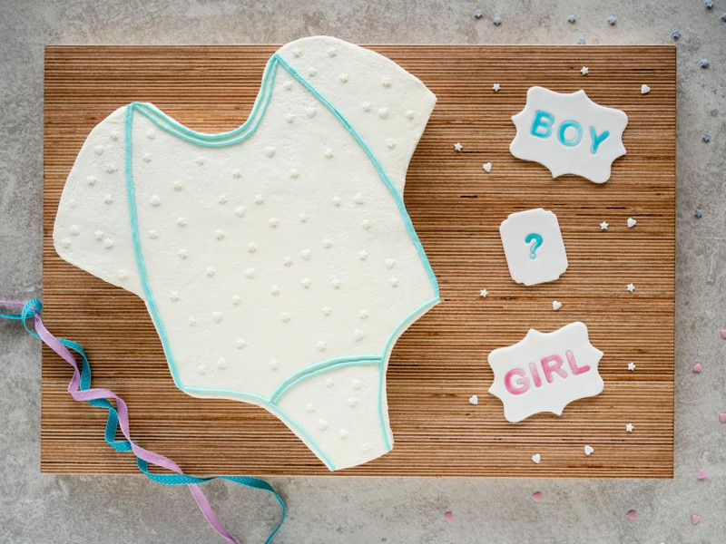 Tort na baby shower udekorowany posypkami i konturami z turkusowej bitej śmietany z ozdobami z masy cukrowej Dr. Oetkera