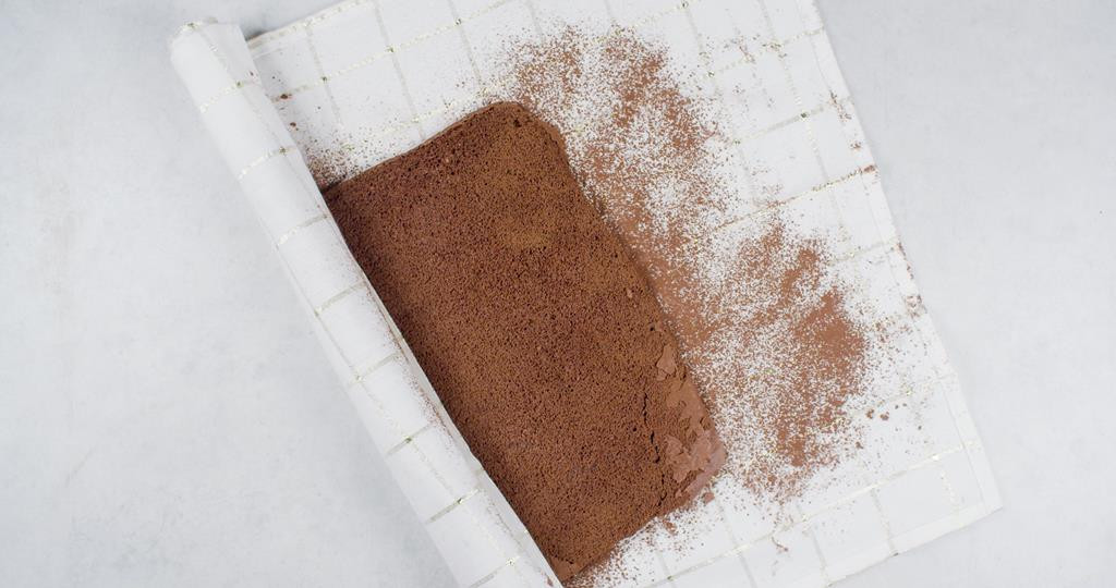 na kuchennej ściereczce biszkoptowe ciasto zwijane w roladę