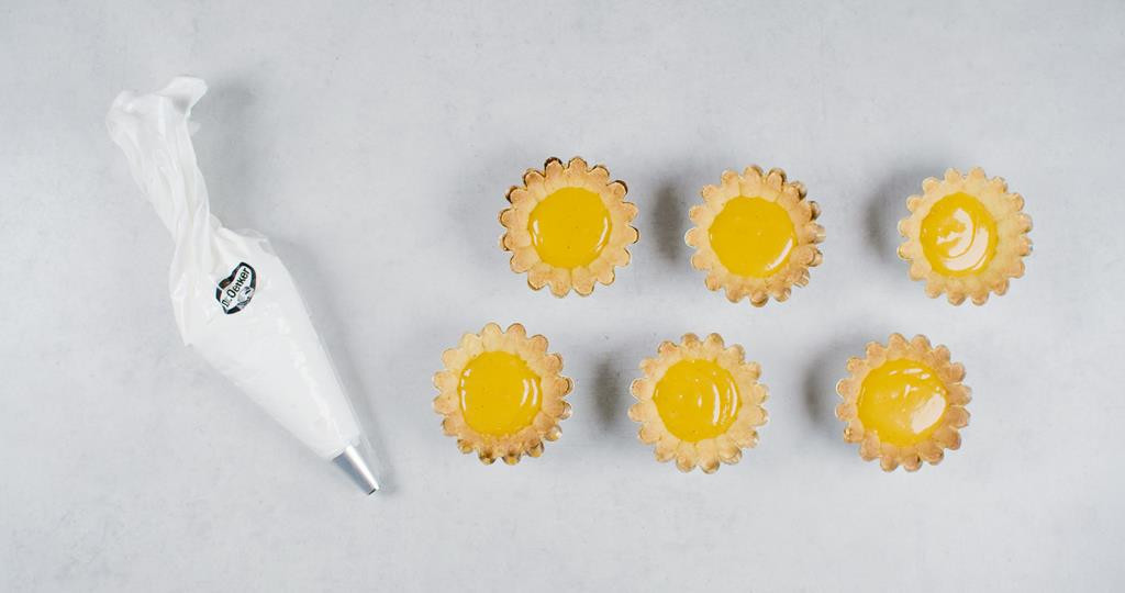 Masa bezowa w rękawie cukierniczym Dr. Oetkera obok tartaletek z kremem cytrynowym