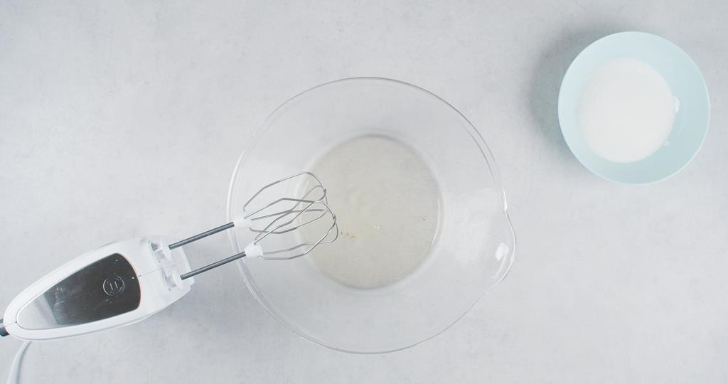 Białka jaj i cukier w osobnych miseczkach, obok mikser