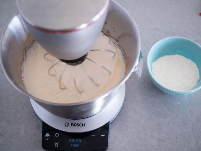 w robocie kuchennym bosch ubita masa jajeczna, obok miseczka z mąką wymieszaną z proszkiem do pieczenia Dr. Oetkera