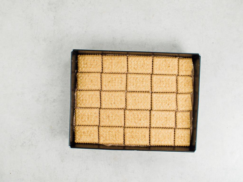 warstwa jasnych herbatników wyłożona na krem czekoladowy rozsmarowany na biszkopcie kakaowym