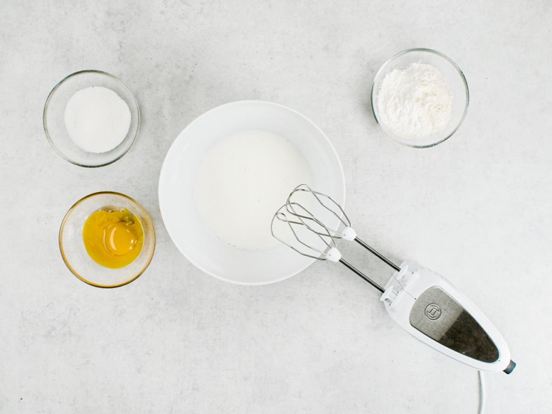 białka jajek ubite mikserem oraz żółtka, cukier i cukier waniliowy w miseczkach