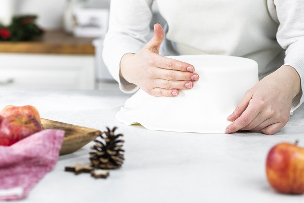 Dociskanie fondantu na tort obłożony masą cukrową białą (fondantem)