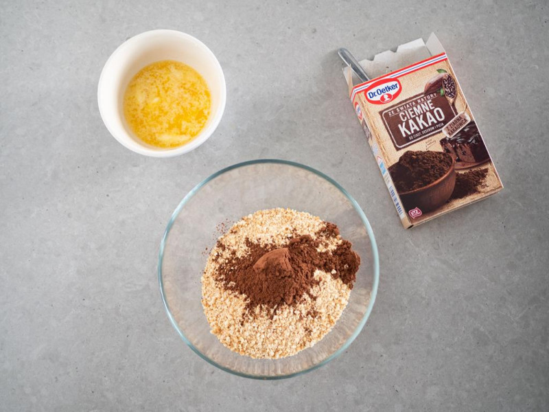 na blacie miseczka z pokruszonymi herbatnikami z ciemnym kakao dr. oetkera oraz miseczka z roztopionym masłem