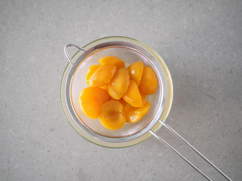 w miceczce odcedzone na sitku brzoskwinie w puszce