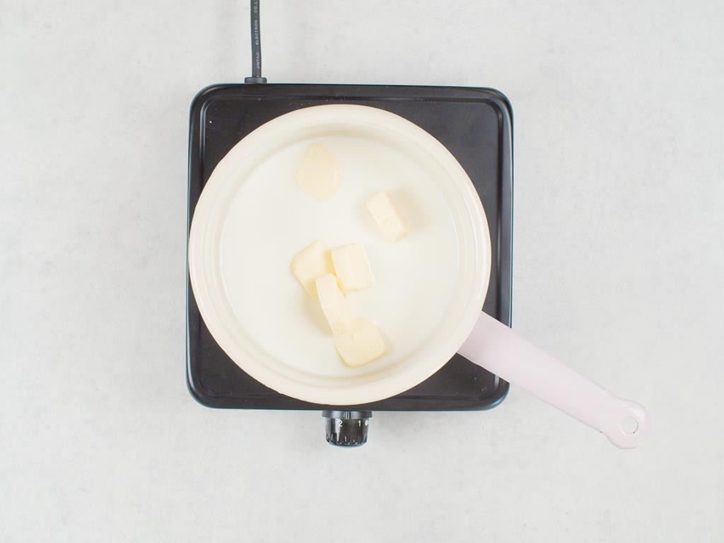 rondelek z mlekiem i masłem na palniku kuchenki