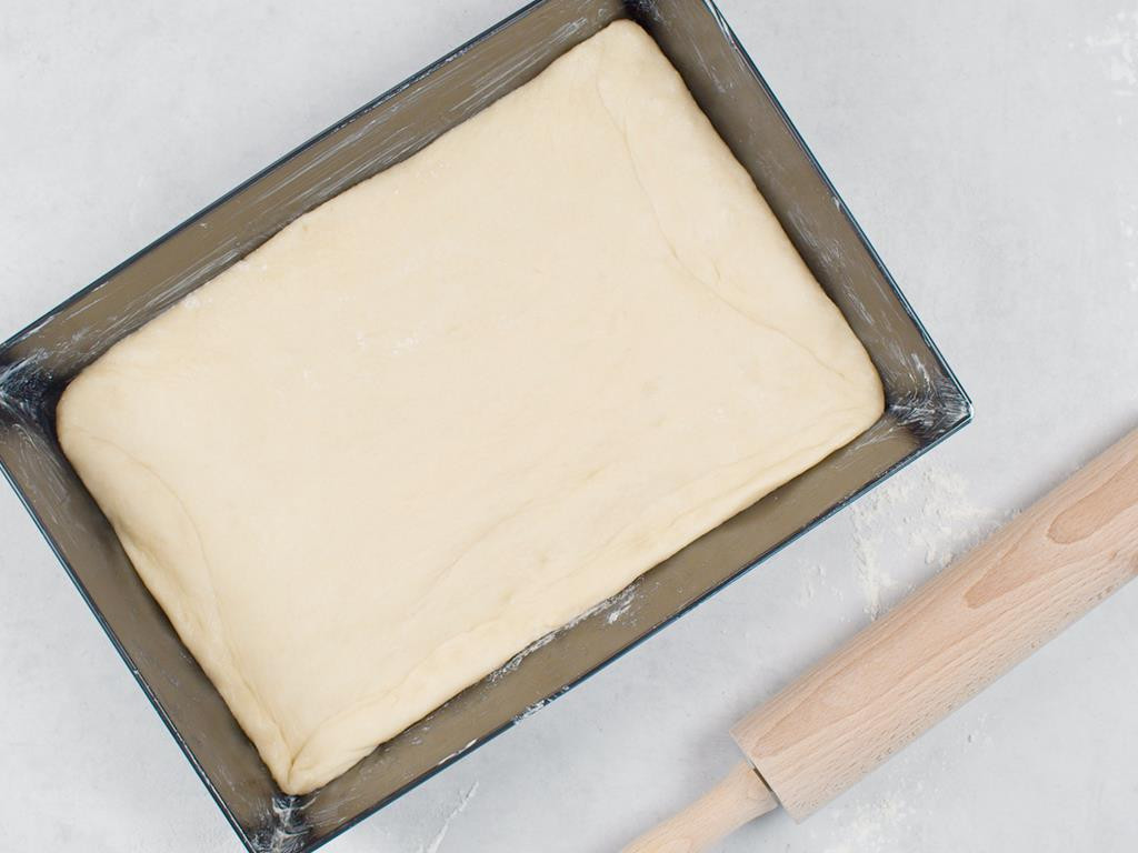 forma wypełniona ciastem drożdżowym, obok wałek